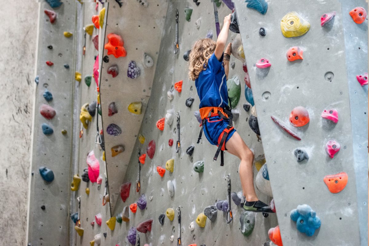 A young girl climbing a colourful structure at an indoor playground in Singa, pore, laughing with excitement