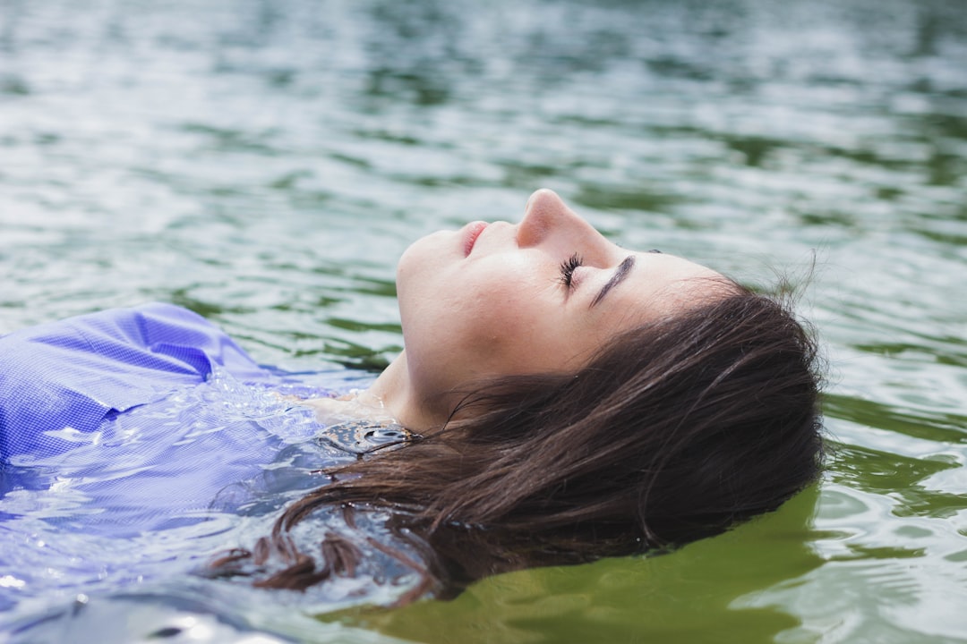 A woman resting peacefully inside a float therapy pod in a Singapore wellness studio, eyes closed in deep relaxation.