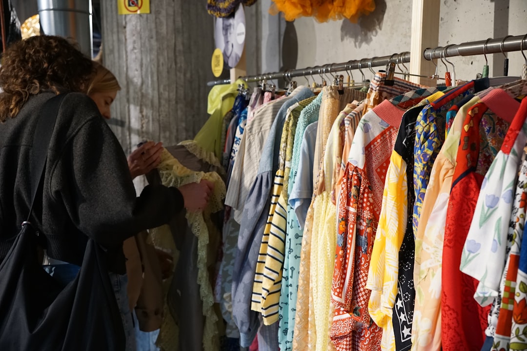 A woman browsing a rack of slow fashion garments in a Singapore boutique, choosing breathable pieces for the wet season.