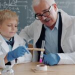 A child conducting hands-on science workshops at a classroom table wearing safety goggles and mixing colourful liquids.