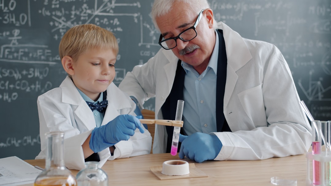 A child conducting hands-on science workshops at a classroom table wearing safety goggles and mixing colourful liquids.
