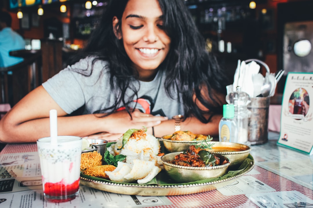 A Singaporean expat woman shares a meal at an outdoor hawker-style food stall, connecting community through food abroad