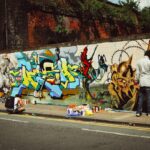A young person painting a large street art mural on an outdoor wall during a Singapore youth programme