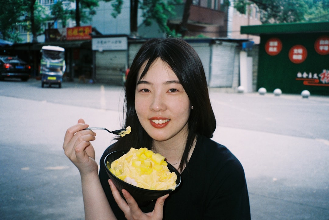 A woman enjoying a bowl of laksa at a busy Singapore hawker centre stall