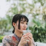 A professional woman beginning her morning routine in Singapore by drinking water at sunrise before the heat builds