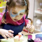 A child enjoying National Day activities at an arts and craft workshop in Singapore, painting red and white designs