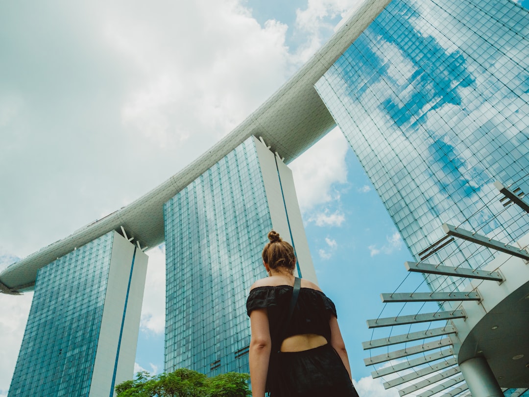 A woman wearing a loose linen outfit walks along a shaded Singapore street, dressed practically for Singapore heat