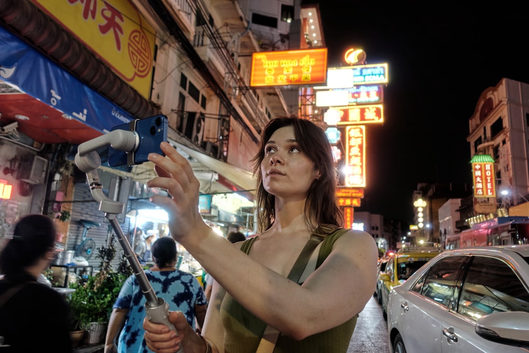 A man uses her smartphone to begin a short film practice on a busy Singapore street