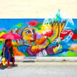 A local artist painting a large Marina Bay mural on an outdoor wall near the waterfront district